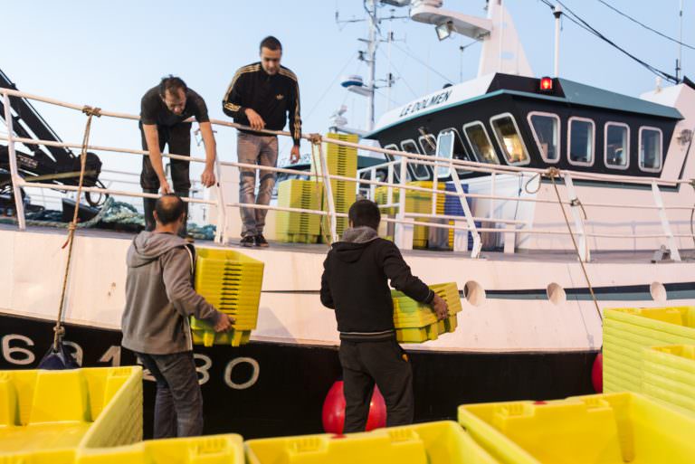 Pêcheurs portant des caisses sur leur bateau